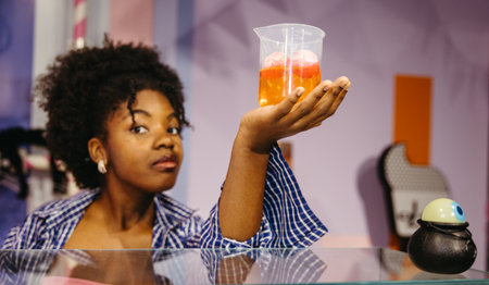 Black woman presenting drink with candy eyeballs in Halloween environmentの写真素材