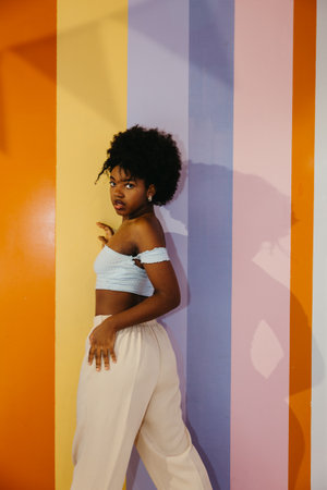 Portrait of confident Black woman posing in front of a colorful striped wallの写真素材