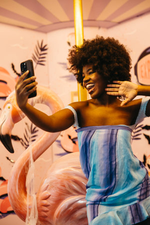 Happy young woman takes a cheerful selfie in a fun, vibrant settingの写真素材