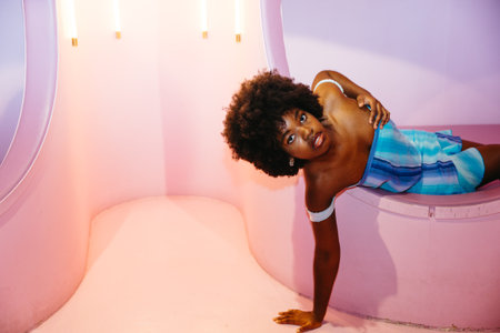 Cheerful young Black woman smiling brightly in a colorful playful setting.の写真素材