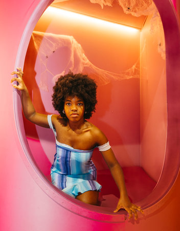 Gorgeous Young Woman Posing in a Pink Halloween-Themed Roomの写真素材