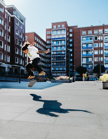 Young skater jumps with style doing a trick in an urban square.の写真素材