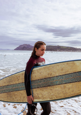 Side view of young female surfer walking with her board at the shore.の写真素材