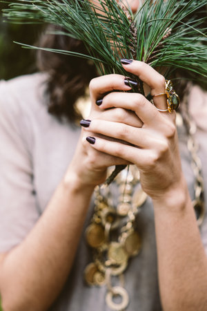 Close-up of woman's hands holding pine branches with bold jewelry in the woodsの写真素材