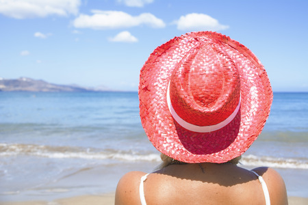 Sitting on the seashore with her red capの写真素材