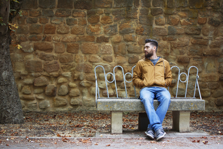 Man sitting on a bench alone, in an autumnal landscape.の写真素材