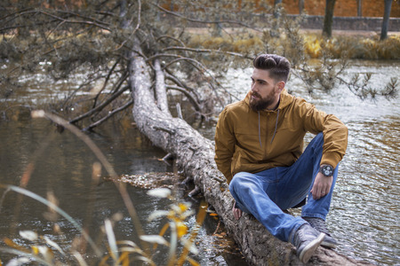 Man sitting on a fallen log on the river.の写真素材