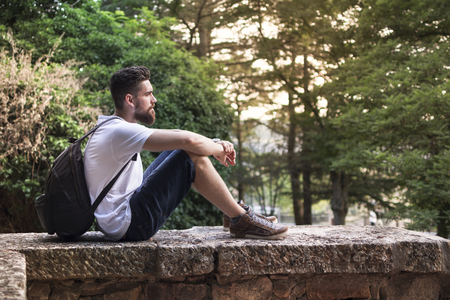 Backpacker, with a beard, sitting enjoying the sunset in nature.の写真素材