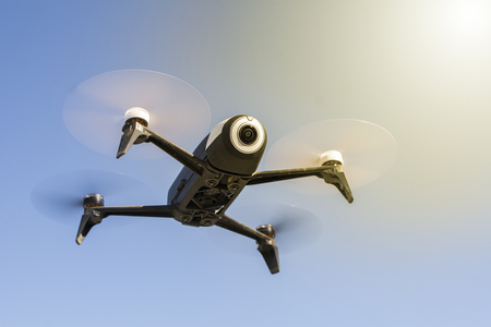 Drone, aircraft that flies without crew, with remote control. Low angle. Blue sky and sunbeam in the background.の写真素材