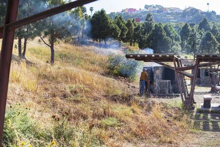person lighting the fire of an outdoor barbecue, in a rural and autumnal landscape.の写真素材