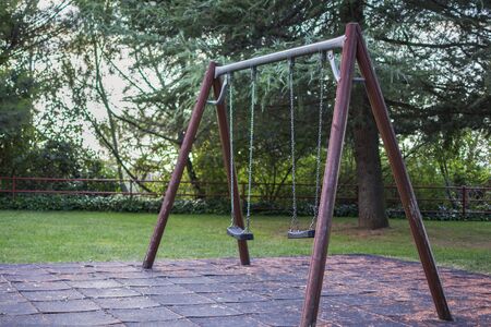 Empty swings in the park, surrounded by nature