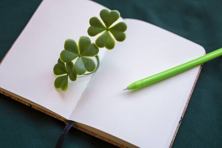 Open and blank luck notebook, with clovers and green pen for St. Patrick's Day.