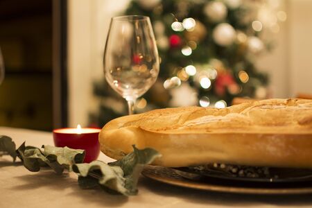 Bread, a glass of wine, dry eucalyptus, a candle, and in the background bokeh with the lights of the...