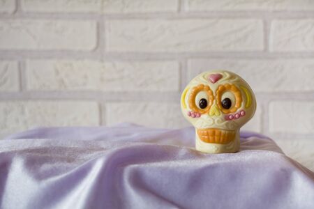 Funny white and orange skull on purple fabric.