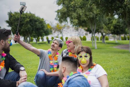 A group of friends with party supplies enjoying together outdoors in the park.