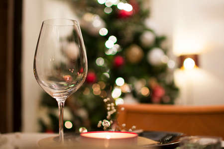 A crystal wine glass close-up on the table, with the bokeh of Christmas tree lights behind.の写真素材