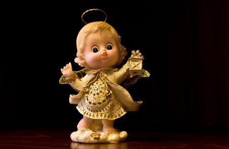 Figurina representing a little angel holding a glim wearing a little golden dressの写真素材