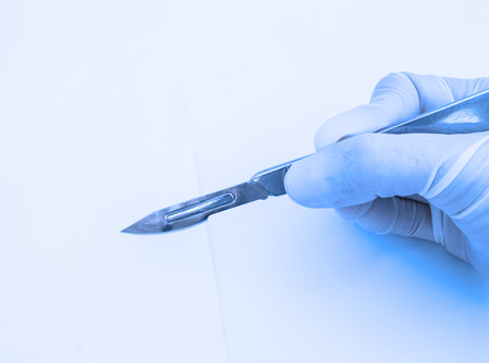 hand with scalpel on blue filterの写真素材