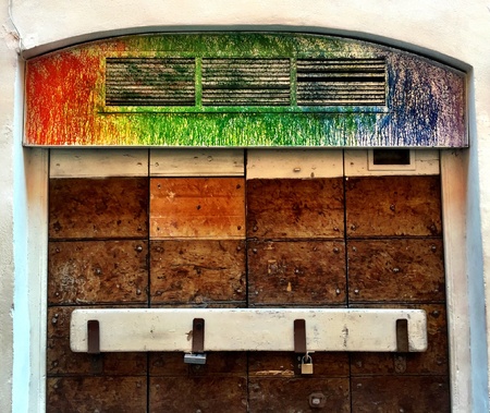 Closed wood door with loopholes painted with colors on topの素材