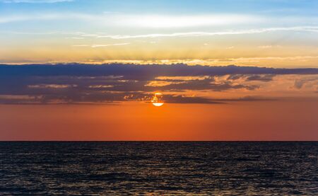 beautiful dawn of late summer with warm colors and dark calm seaの写真素材