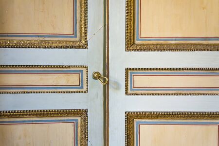 an old painted door decorated with gold, blue and red linesの写真素材