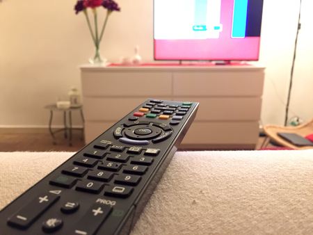 Close up of a remote controller with a television on backgroundの写真素材