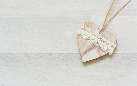 white wooden heart placed nicely on a wood backgroundの写真素材