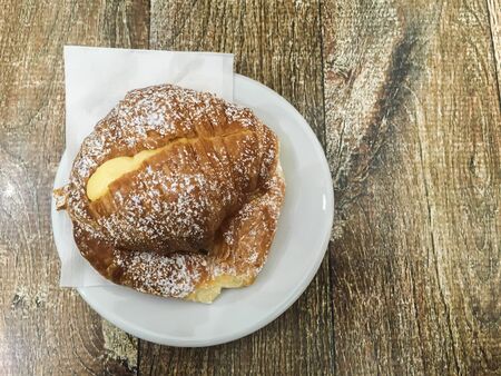 Aerial view of a creamy croissant on a wooden tableの写真素材