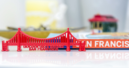 Golden Gate Bridge miniature with San Francisco city guide and a blurred cable car miniature in...