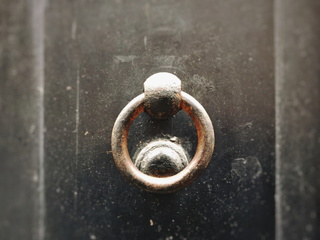 close up of an ancient round clapper on a dark wooden doorの写真素材