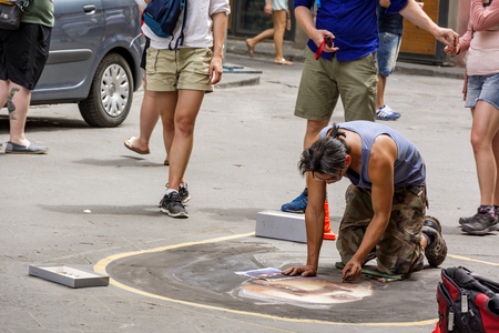 Florence, Italy, June 2015: a street artist (called "madonnaro") kneeling draws the face of a woman on the street with a colored chalkのeditorial素材