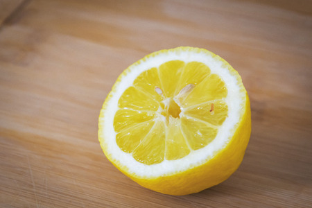 Half of a lemon with a bone on a light wooden boardの写真素材