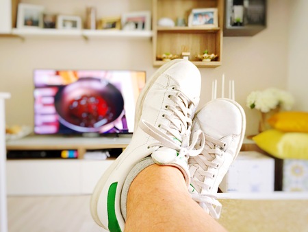Watching cooking recipes on television. Focus on white shoesの写真素材