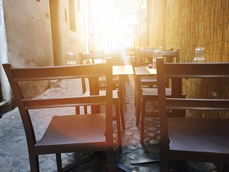 Chairs and tables of a restaurant with sunlight in backlightの写真素材