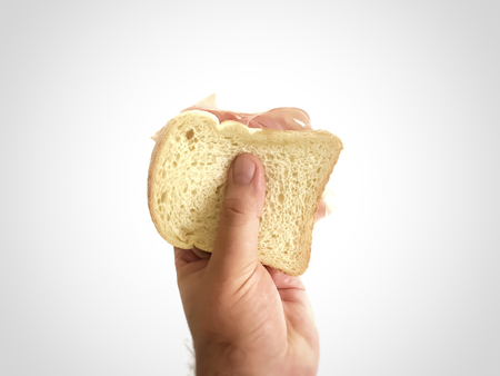 Male hand holding a baked ham sandwich. Junk Food conceptの写真素材