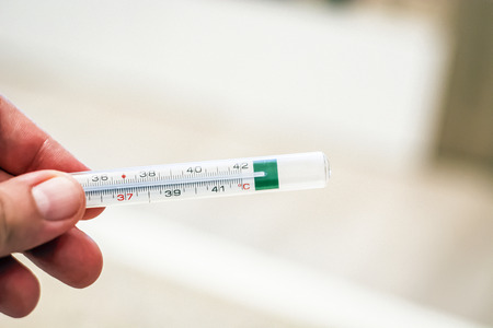 Thermometer held by a male hand. Healthcare conceptの写真素材