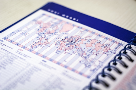 Spiral diary open on the page with the world map with time zones. Business and world travelの写真素材