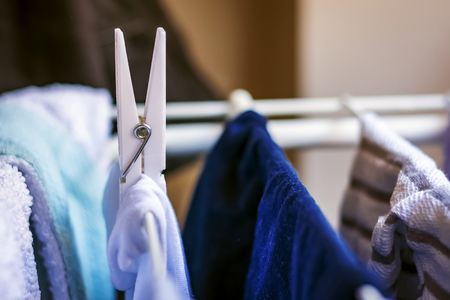 a white clothespin hangs a clothes hanging on a drying rack. Drying laundry