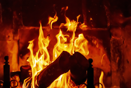 Fire burns in the fireplace powered by wooden logs. Heat and glow.の写真素材