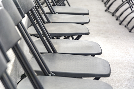 Rows of black folding chairs empty in a conference roomの写真素材