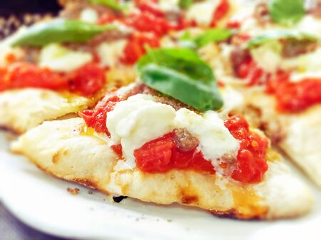 close-up view of a margherita pizza with fresh tomatoes, mozzarella cheese and basil leaves. Typical...
