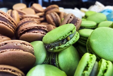 many colorful macaroons biscuits arranged disorderly. In the foreground, the green ones with pistachio flavor. Baked cake with various colorsの写真素材