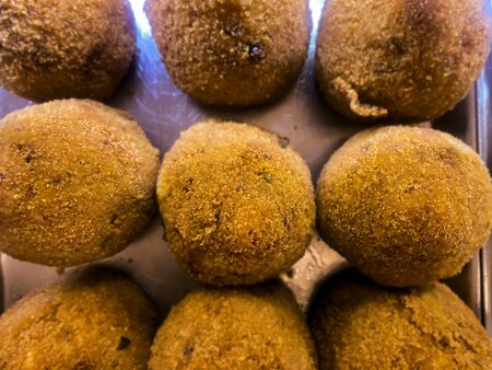Sicilian arancini arranged on a metal tray and displayed for sale. Typical Sicilian recipe. Famous...