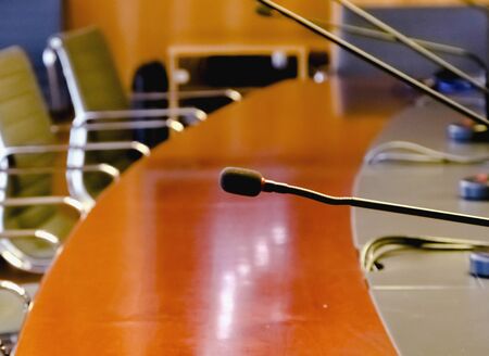 a table microphone in a board room with a wooden table and a row of empty chairs. Business and management concept. Board of directorsの写真素材