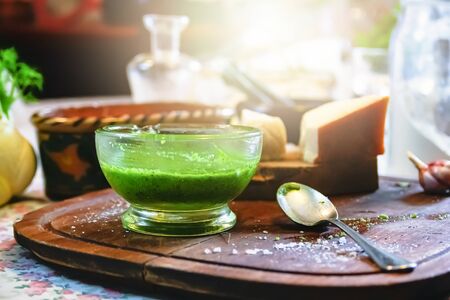 a glass bowl with homemade pesto sauce on a wooden table in a rustic Italian kitchen. Parmesan cheese and pecorino cheese. Traditional Italian cuisine.の写真素材