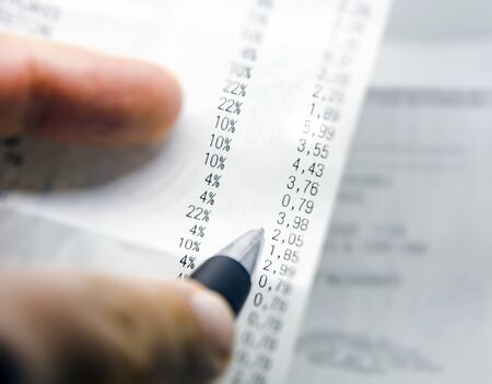 Checking a paper receipt with the list of economic issues. Business and economics. Family financial budgetの写真素材