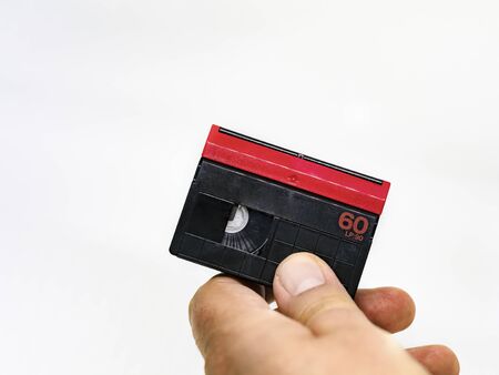 male hand holding a Mini DV format video cassette isolated on a white background. MiniDV cassettes, had been intended for amateur use, but have become accepted in professional productions as wellの写真素材