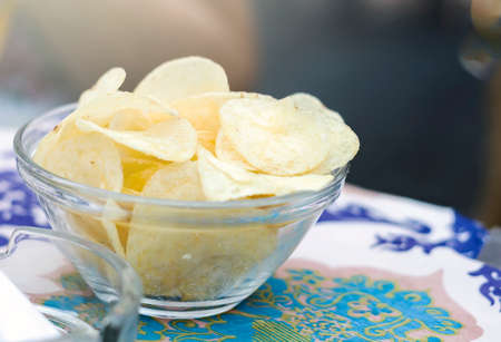 potato chips inside a glass bowl on a bar table. Appetizer and junk food