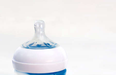 the transparent silicone teat of a blue baby bottle isolated on a white background.の写真素材