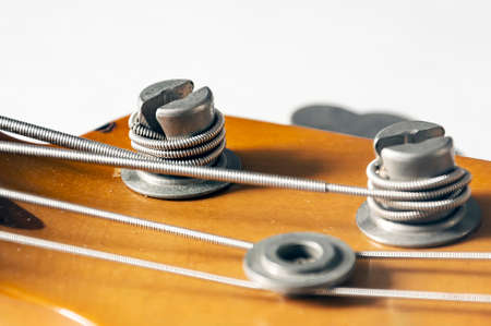 Detail of a tuning post on the wooden headstock of an electric bass guitar. Musical instruments and mechanics for string tuning.の写真素材